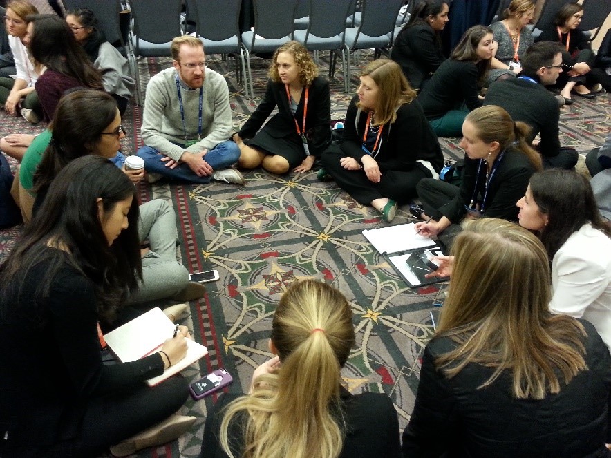 IDEO.orgâs Owen Sanderson discusses a rechargeable solar lantern (held on far right) with attendees, as part of a physical product gallery during a 15 minute case study â including water filters, solar lamps, adjustable spectacles, and clean stoves.  